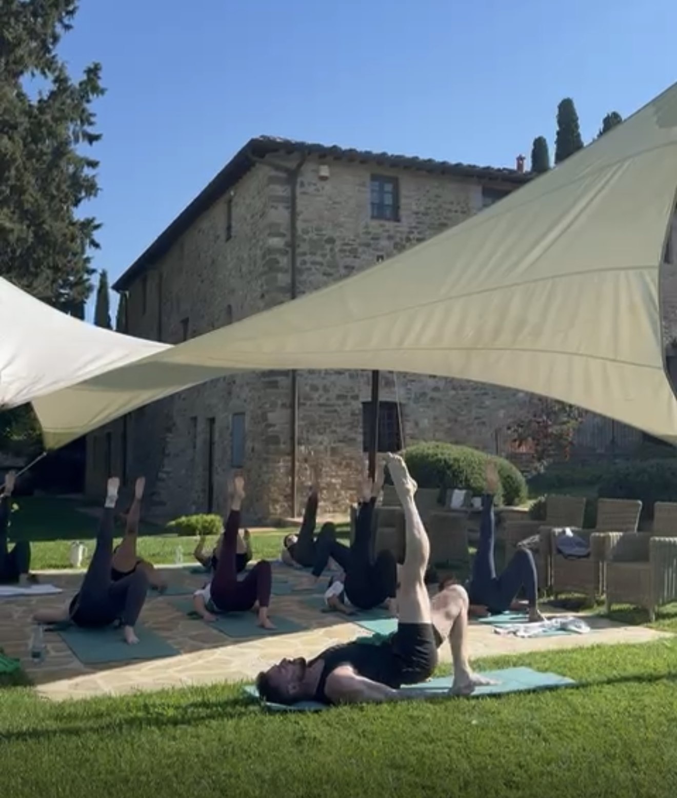Group Pilates class under the shade sail